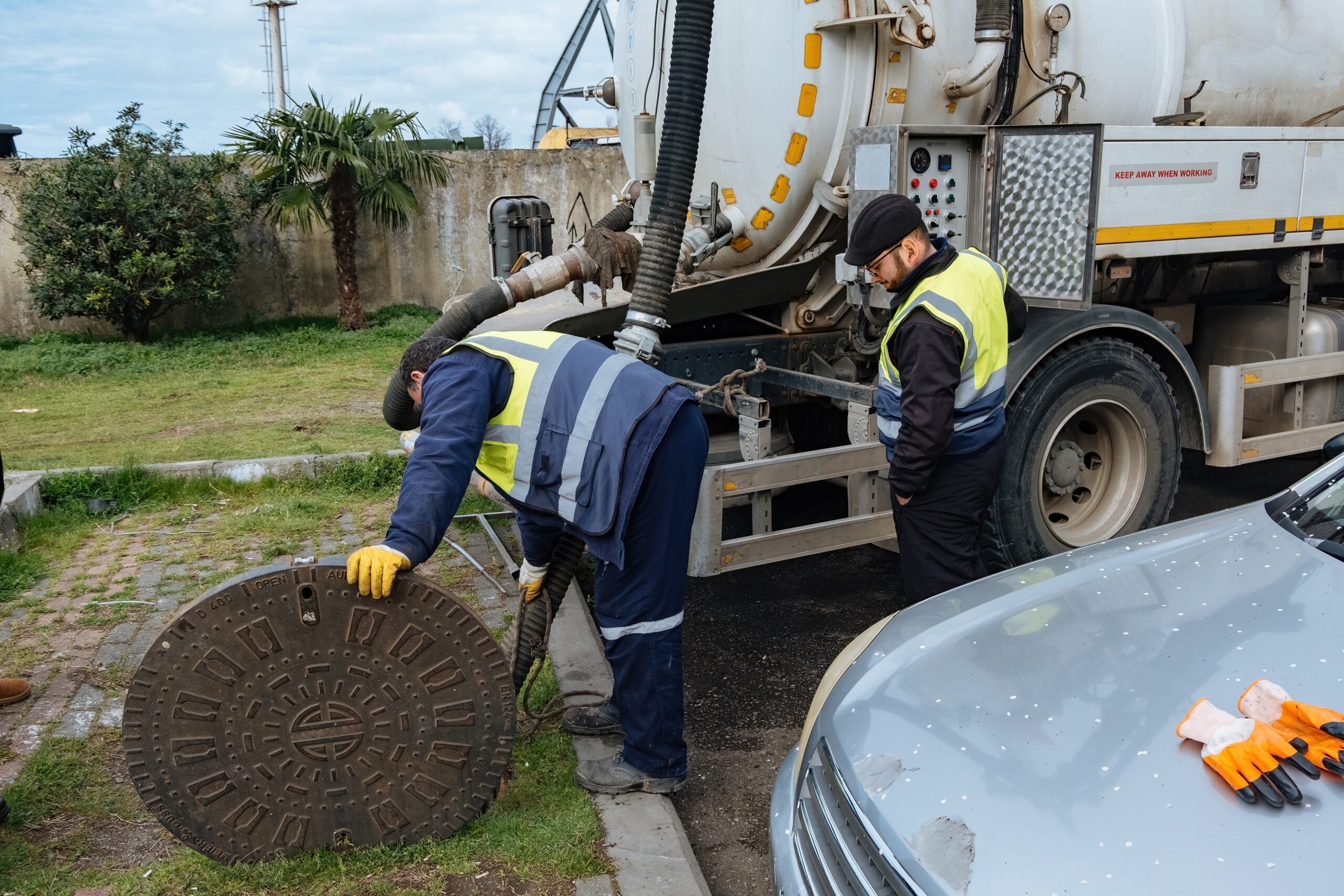 Tidy Tank Plumbing, Sewer, and Septic crew in work truck lifting up septic tank cover to perform maintenance.